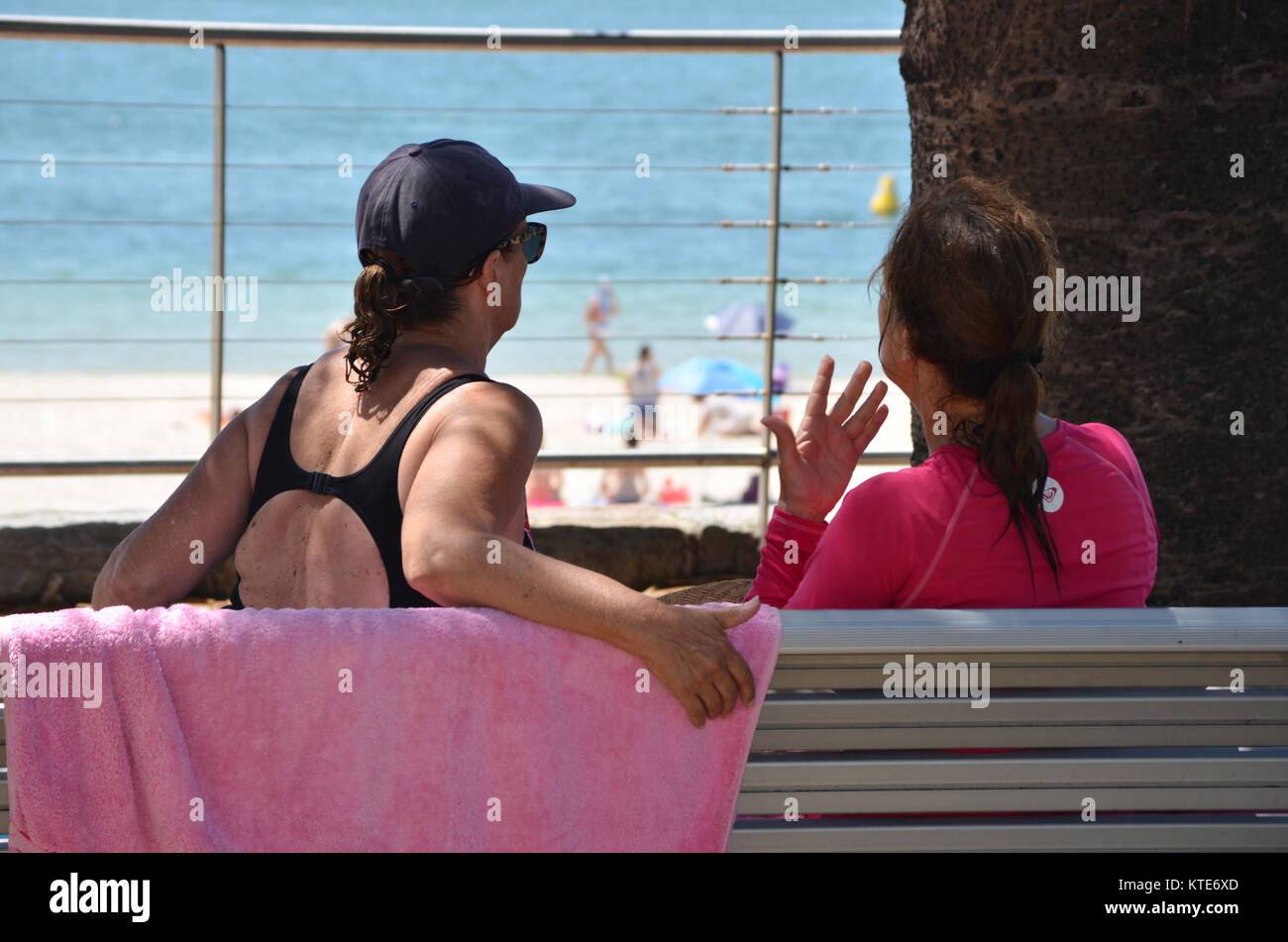 Confida in me due femmine aventi una conversazione su un banco di lavoro con vista sull'oceano. Foto Stock