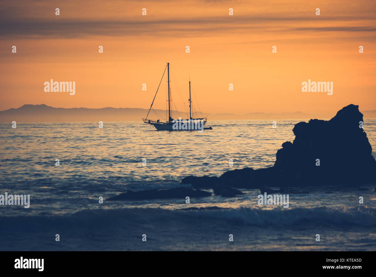 Silhouette di una barca a vela al tramonto in barca a vela da Newport Beach in California con Isola di Santa Catalina in background Foto Stock