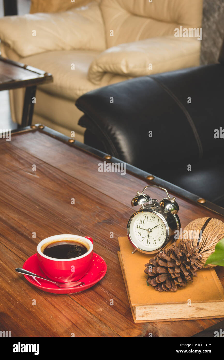 Nero caffè nella tazza di rosso con libro e orologio sulla tavola in cafe Foto Stock