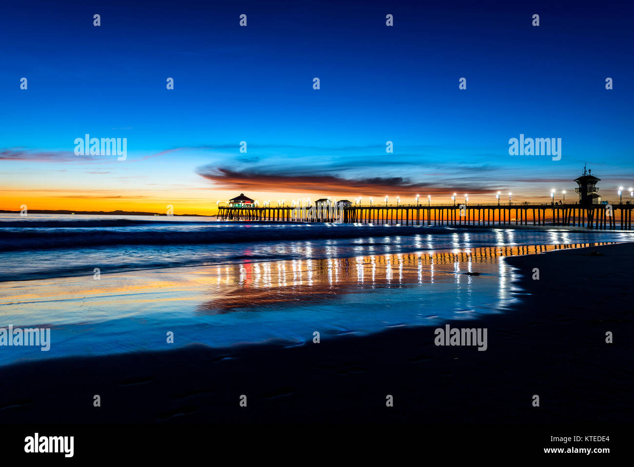 Paesaggio surreale come il sole tramonta sotto l'orizzonte lungo Huntington Beach, colata di un bagliore bellissimo e tranquillo paesaggio. Foto Stock