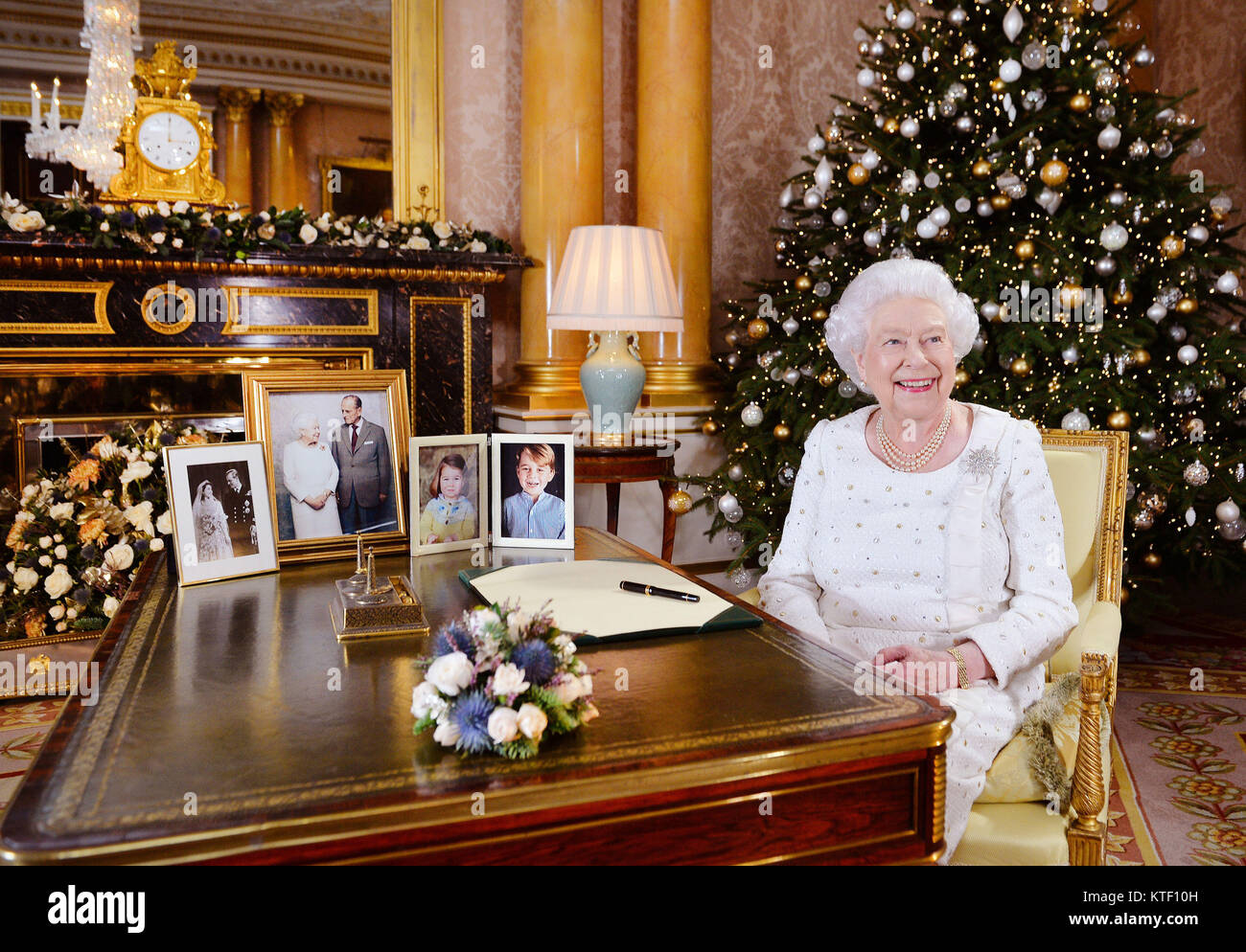 La regina Elisabetta II si siede a una scrivania in camera 1844 a Buckingham Palace di Londra, dopo la registrazione del suo giorno di Natale broadcast per il Commonwealth. Foto Stock