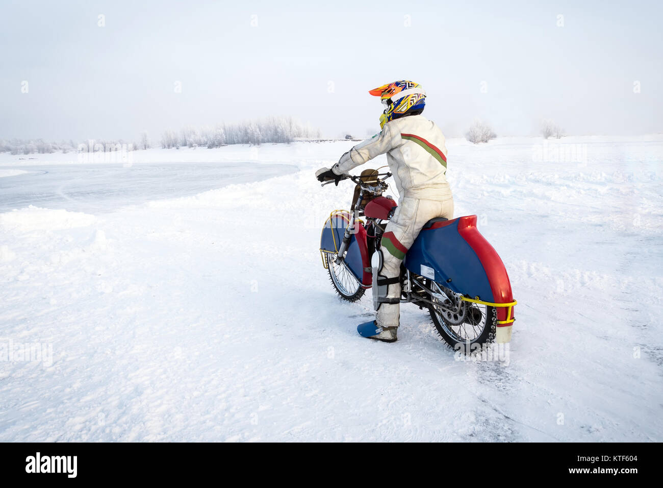 Motociclista in un vestito bianco Preparazione per andare sulla pista di ghiaccio. La concorrenza per la superstrada in inverno. svolta pericolosa. extreme sport invernali su Foto Stock