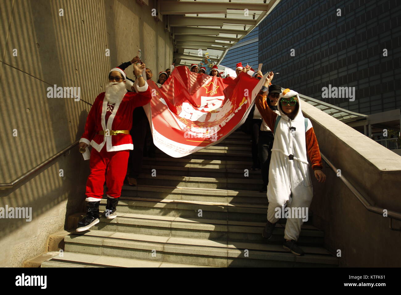 Hong Kong, Cina. 24 dicembre, 2017. Gruppo di cittadini vestito in Xmas constumes scendere dal passo al di fuori del governo sede generale con un banner che legge anti-LINK. Un gruppo di interessati in scena la protesta contro un mega-investitore immobiliare link che è stata la trasformazione di ex wet-mercati in un high-consumatore-shopping mirato portici che ha portato inconvinience e l'inflazione dei prezzi tra il basso reddito le comunità di Hong Kong.24-Dic 2017 Hong Kong.ZUMA/Liau Chung Ren Credito: Liau Chung Ren/ZUMA filo/Alamy Live News Foto Stock