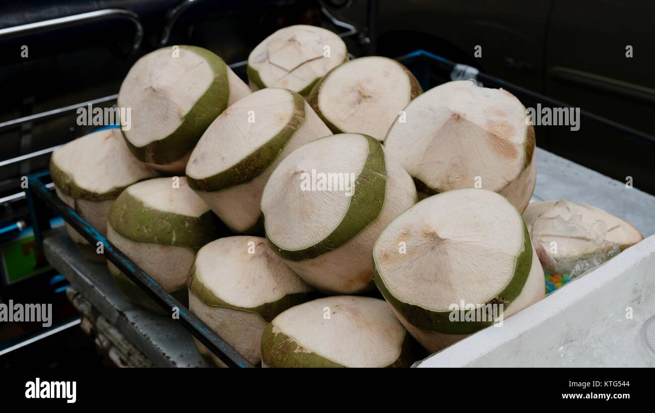 Fresco taglio noci di cocco clima caldo frutta tropicale da un fornitore marciapiede Bangkok Thailandia Foto Stock