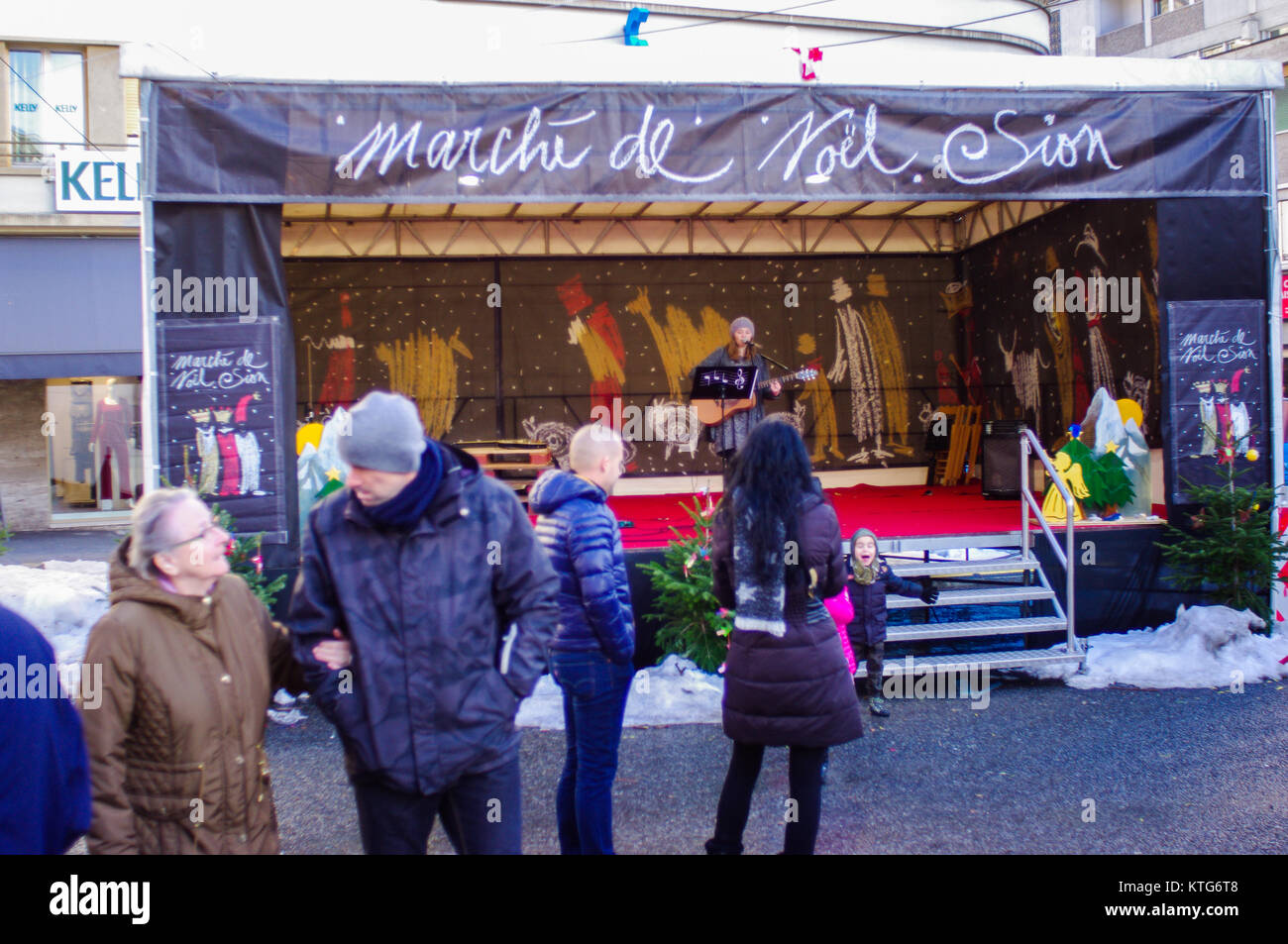 La gente fuori per le Marche de Noel Sion dove sono Chistmas shopping. Fascia giocare in concerto. Foto Stock