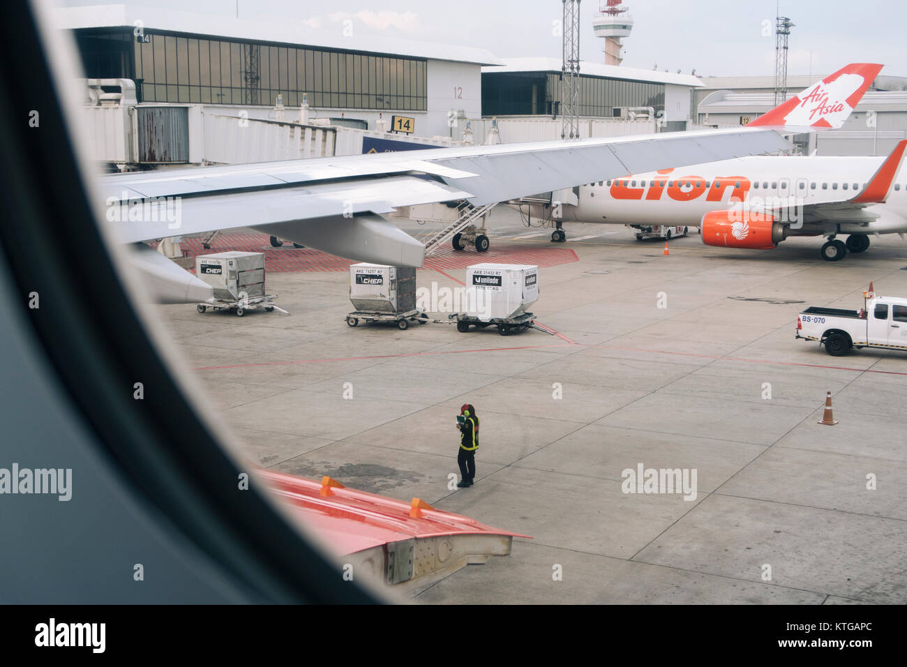 Un aeroporto equipaggio di manutenzione prima del decollo visto dal sedile passeggero di AirAsia X all'Aeroporto Internazionale di Don Muang. Foto Stock