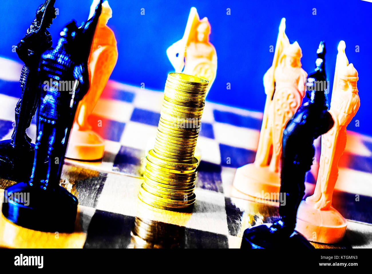 Le monete sono impilati su una scacchiera circondato da bianco e nero a scacchi pezzi, il concetto di leadership, il concetto di business Foto Stock