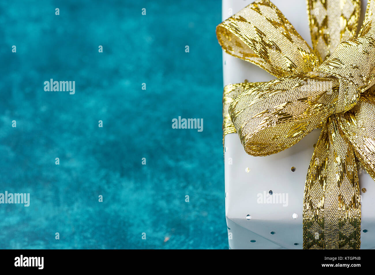 Elegante confezione regalo avvolto in grigio argento con carta a pois Golden nastro blu su sfondo turchese. Compleanno di San Valentino Festa della Mamma Natale ne Foto Stock