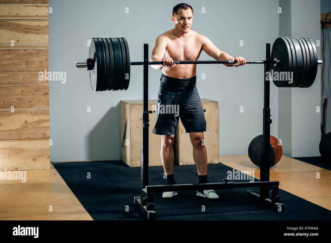 Uomo in piedi da un barbell cavalletto di sicurezza in una palestra Foto Stock