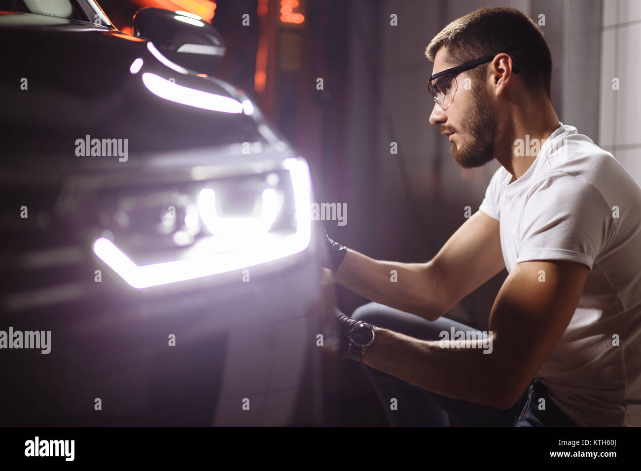 Dettagli auto - uomo con lucidatrice orbitale nel negozio di riparazioni auto. Messa a fuoco selettiva. Foto Stock