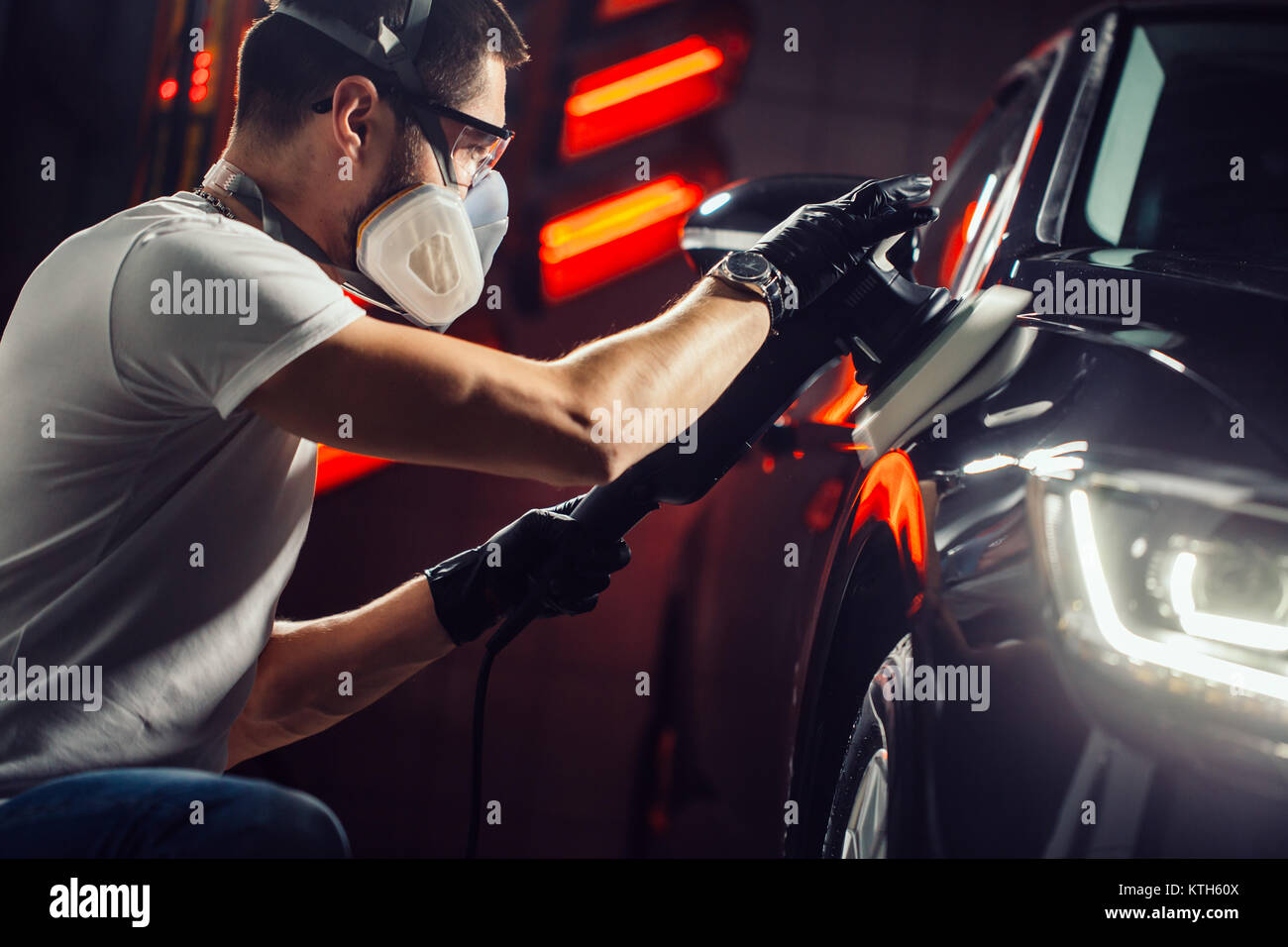 Dettagli auto - uomo con lucidatrice orbitale nel negozio di riparazioni auto. Messa a fuoco selettiva. Foto Stock