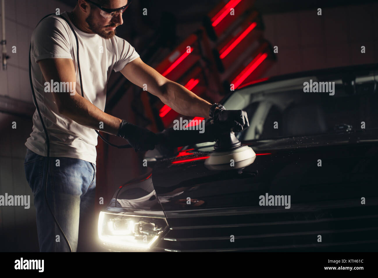 Dettagli auto - uomo con lucidatrice orbitale nel negozio di riparazioni auto. Messa a fuoco selettiva. Foto Stock