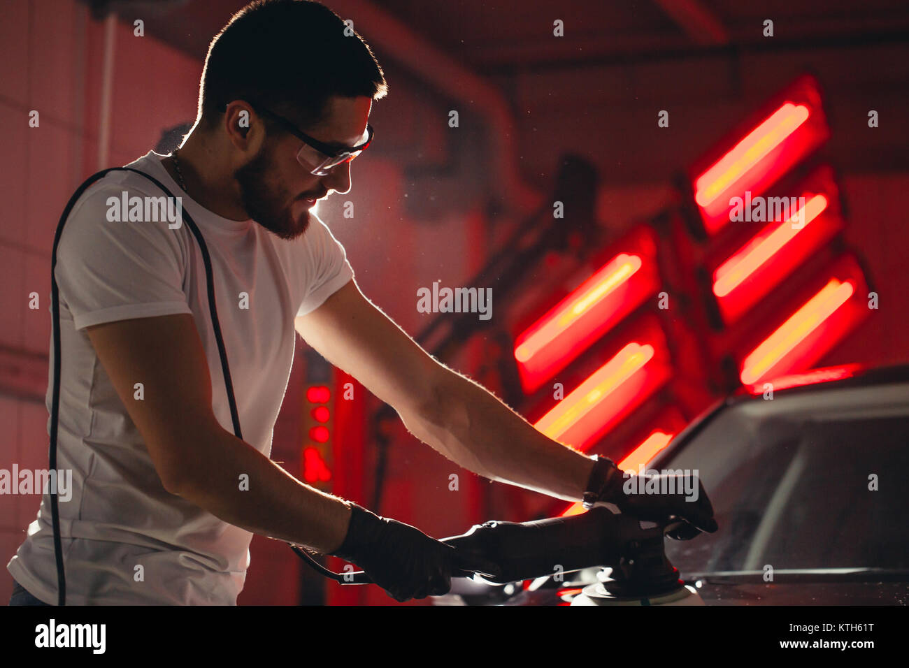 Dettagli auto - uomo con lucidatrice orbitale nel negozio di riparazioni auto. Messa a fuoco selettiva. Foto Stock