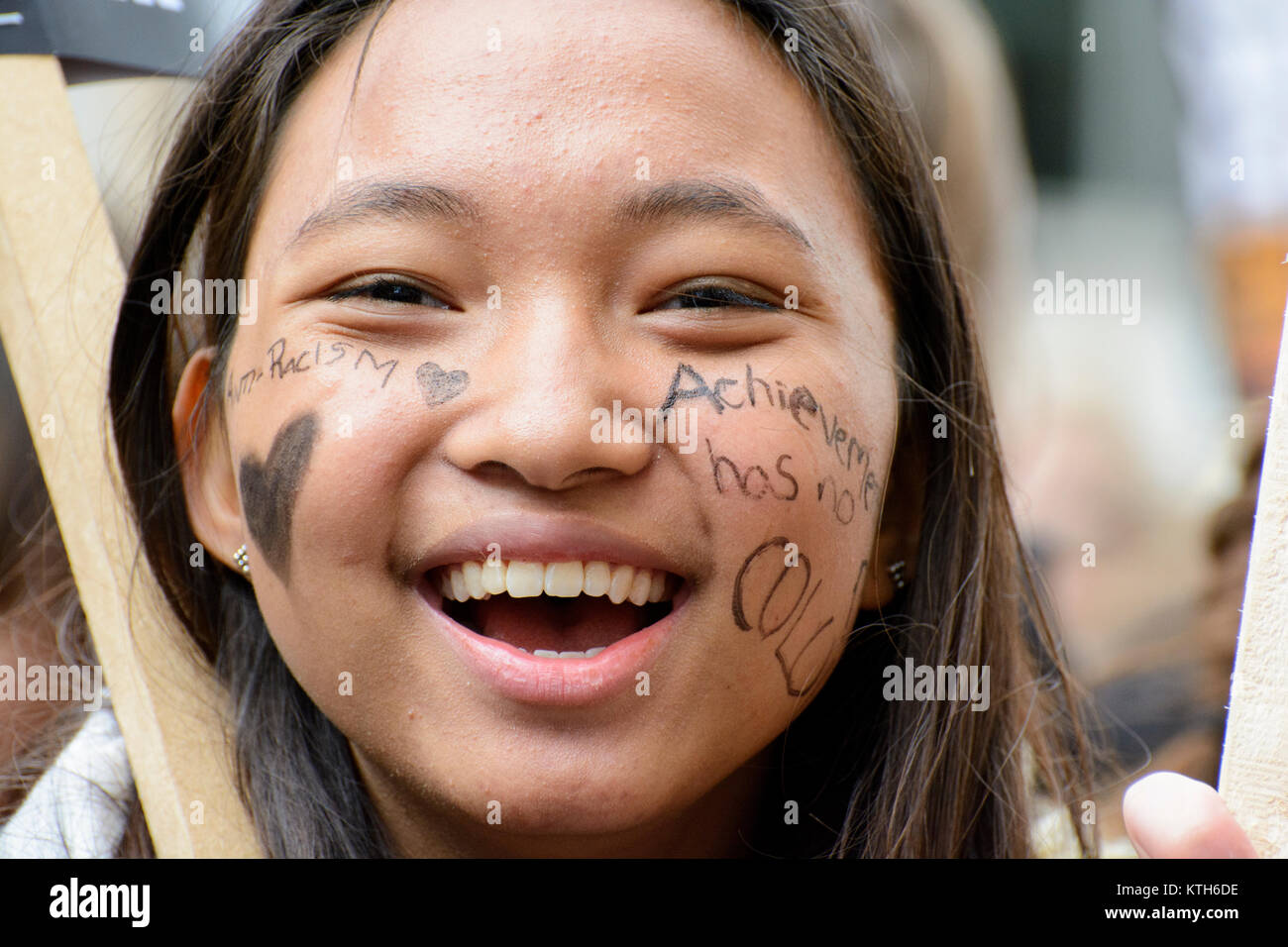 Internazionale delle Nazioni Unite Giornata Anti-Racism: sorridente anti-razzismo protester porta un messaggio scritto sulla faccia "Achievement non ha colore' di Londra, Regno Unito. Foto Stock