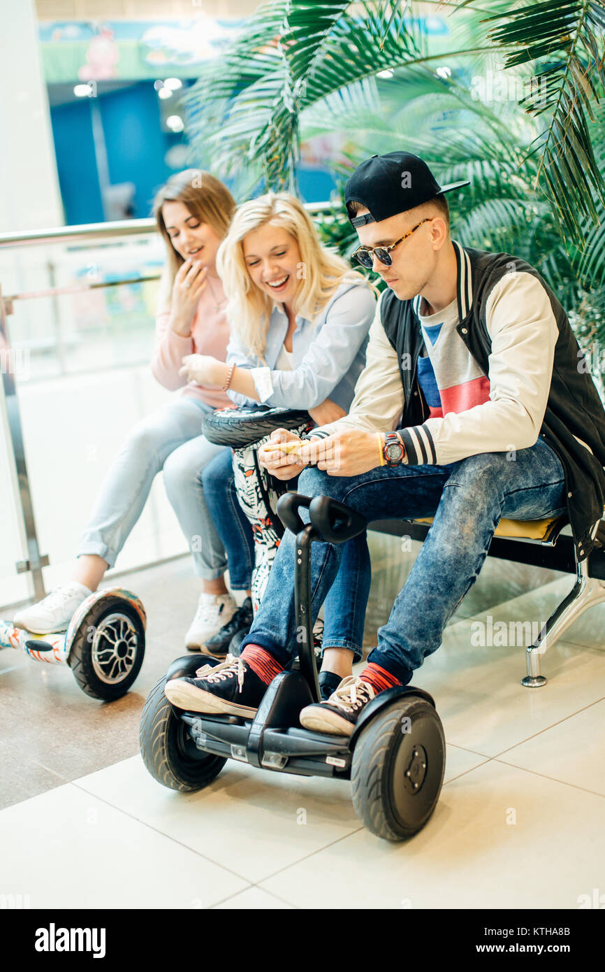 Gruppo di persone su scooter elettrico hoverboard seduto al banco di lavoro e utilizzando il telefono Foto Stock