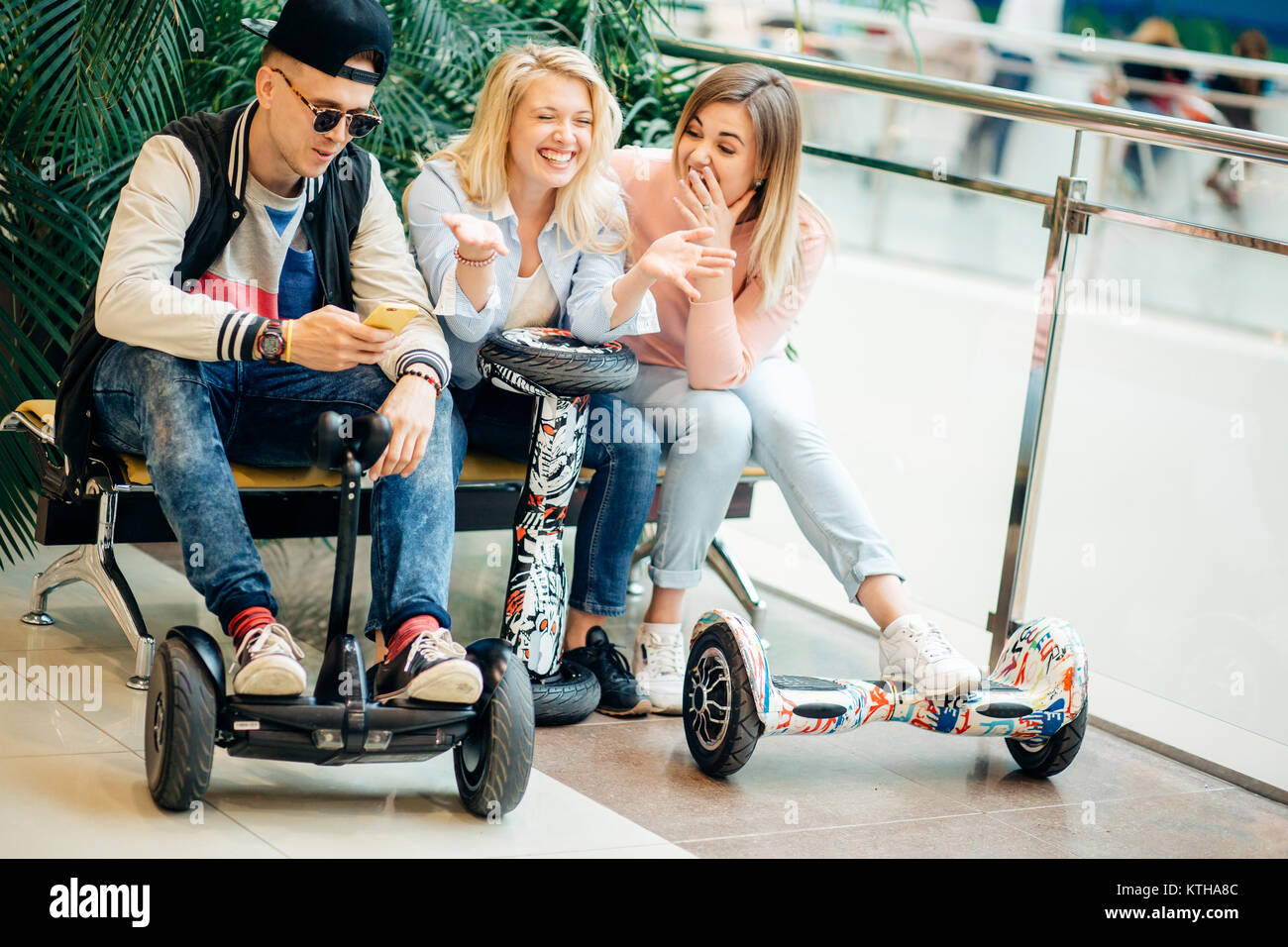 Gruppo di persone su scooter elettrico hoverboard seduto al banco di lavoro e utilizzando il telefono Foto Stock