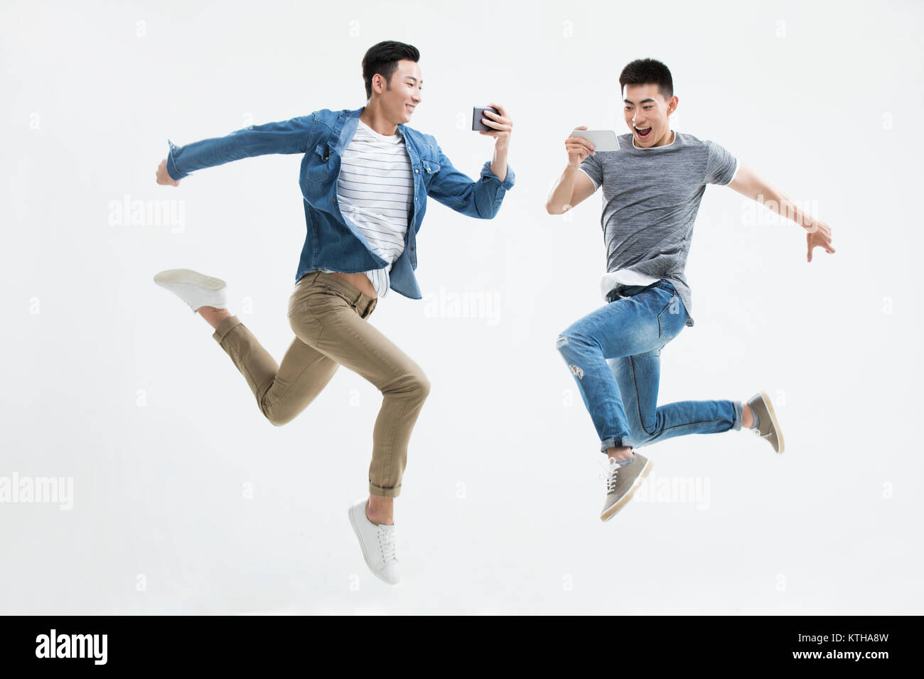 Giovani uomini jumping con uno smart phone Foto Stock