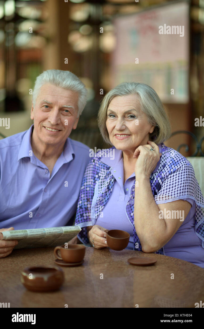 Felice coppia senior seduta a tavola, uomo azienda giornale, donna bere il tè Foto Stock