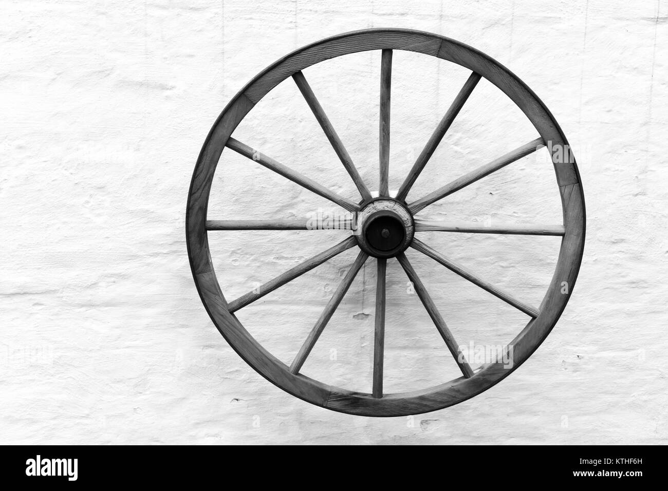 Vecchio carrello di legno ruota sospesa sulla parete rurale, in bianco e nero Foto Stock