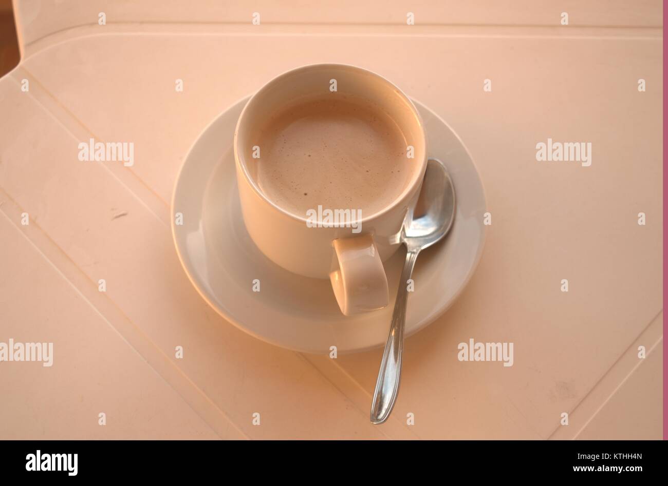 Un caldo il caffè amaro su un bianco tavolo di plastica con un cucchiaio e piattino sotto in attesa di qualcuno a bere in una zolla di terreno meteo nel dicembre 2017. Foto Stock