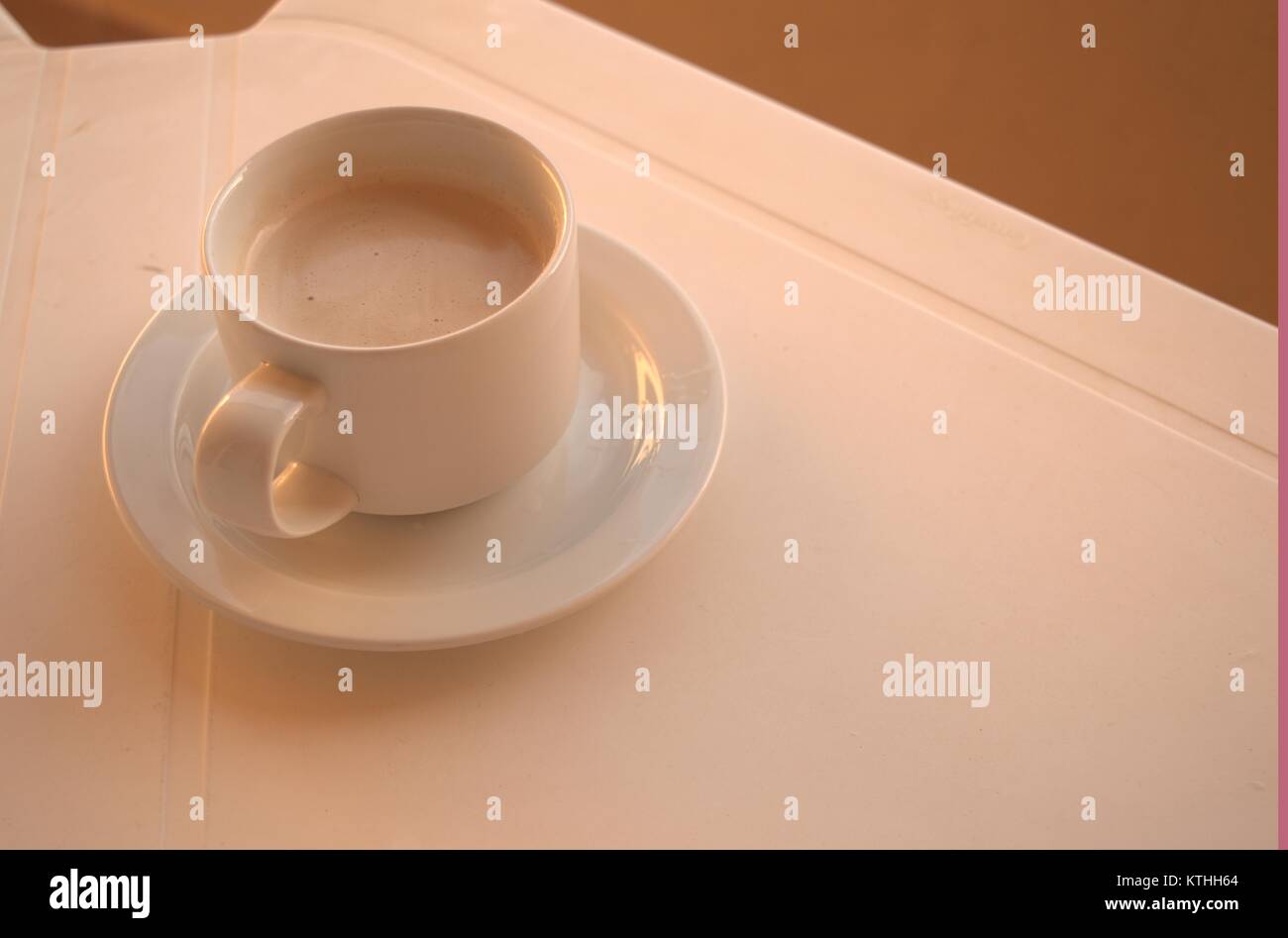 Un caldo il caffè amaro su un bianco tavolo di plastica con un cucchiaio e piattino sotto in attesa di qualcuno a bere in una zolla di terreno meteo nel dicembre 2017. Foto Stock