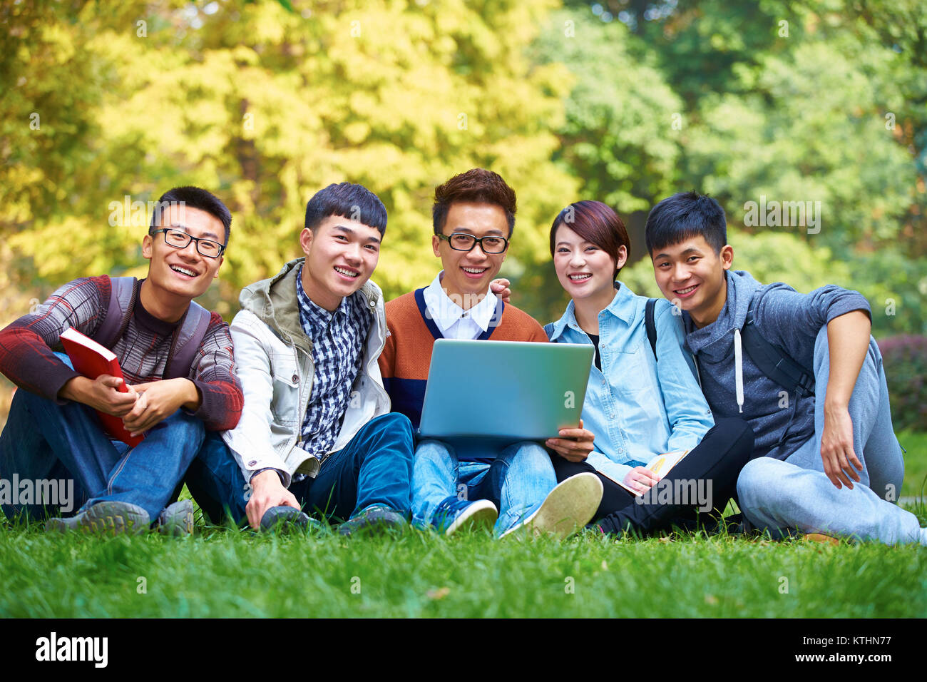 Gruppo di fice felice asian degli studenti che utilizzano computer portatile in campus Foto Stock