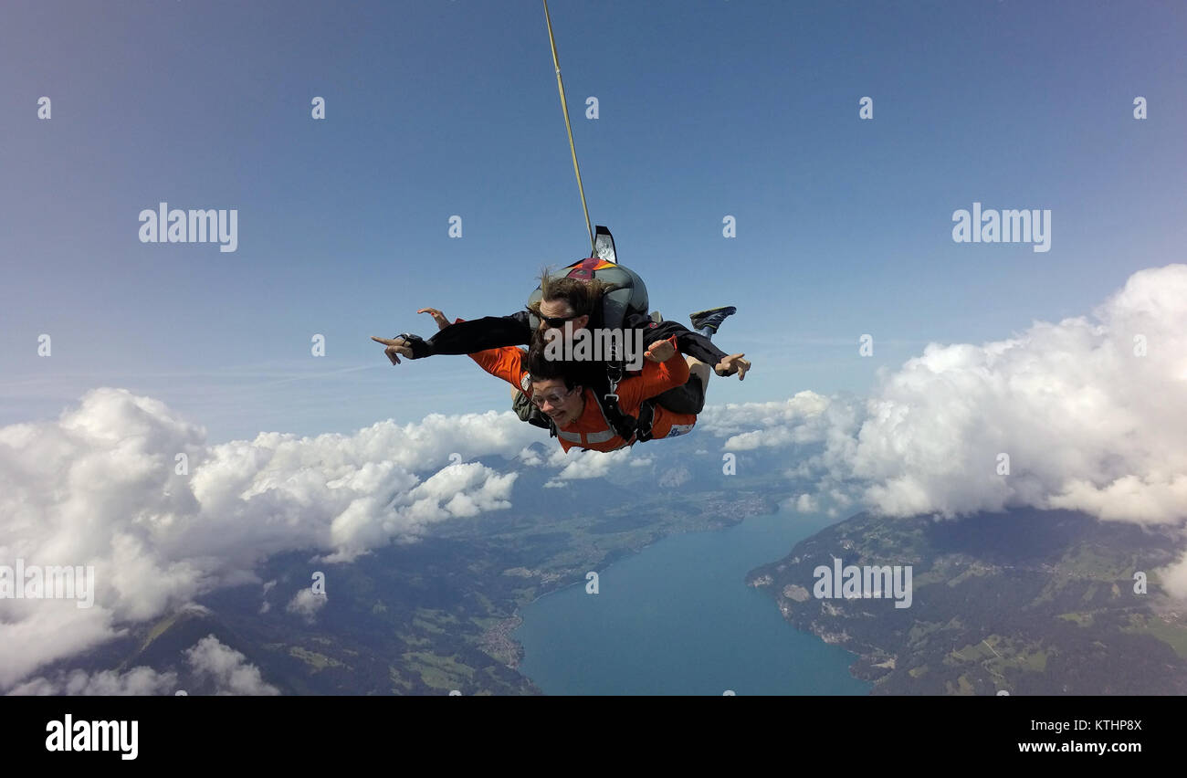 Questo lo skydiving in tandem e team sta godendo il volo panoramico su una bella montagna e lago di zona. Check out la faccina sorridente dal passeggero! Foto Stock