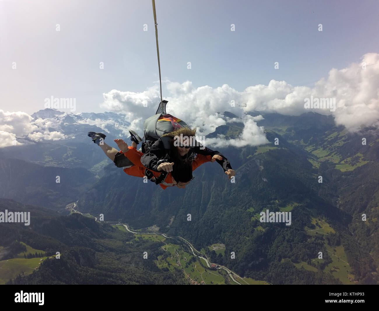Questo lo skydiving in tandem e team sta godendo il volo panoramico su una bella montagna e lago di zona. Check out la faccina sorridente dal passeggero! Foto Stock