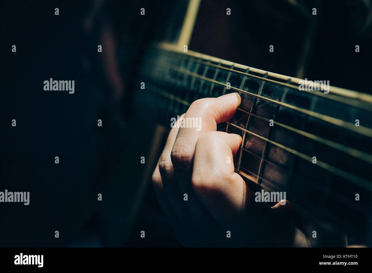 Close up di mani femminili alla chitarra fret mentre si esegue in fase di buio Foto Stock
