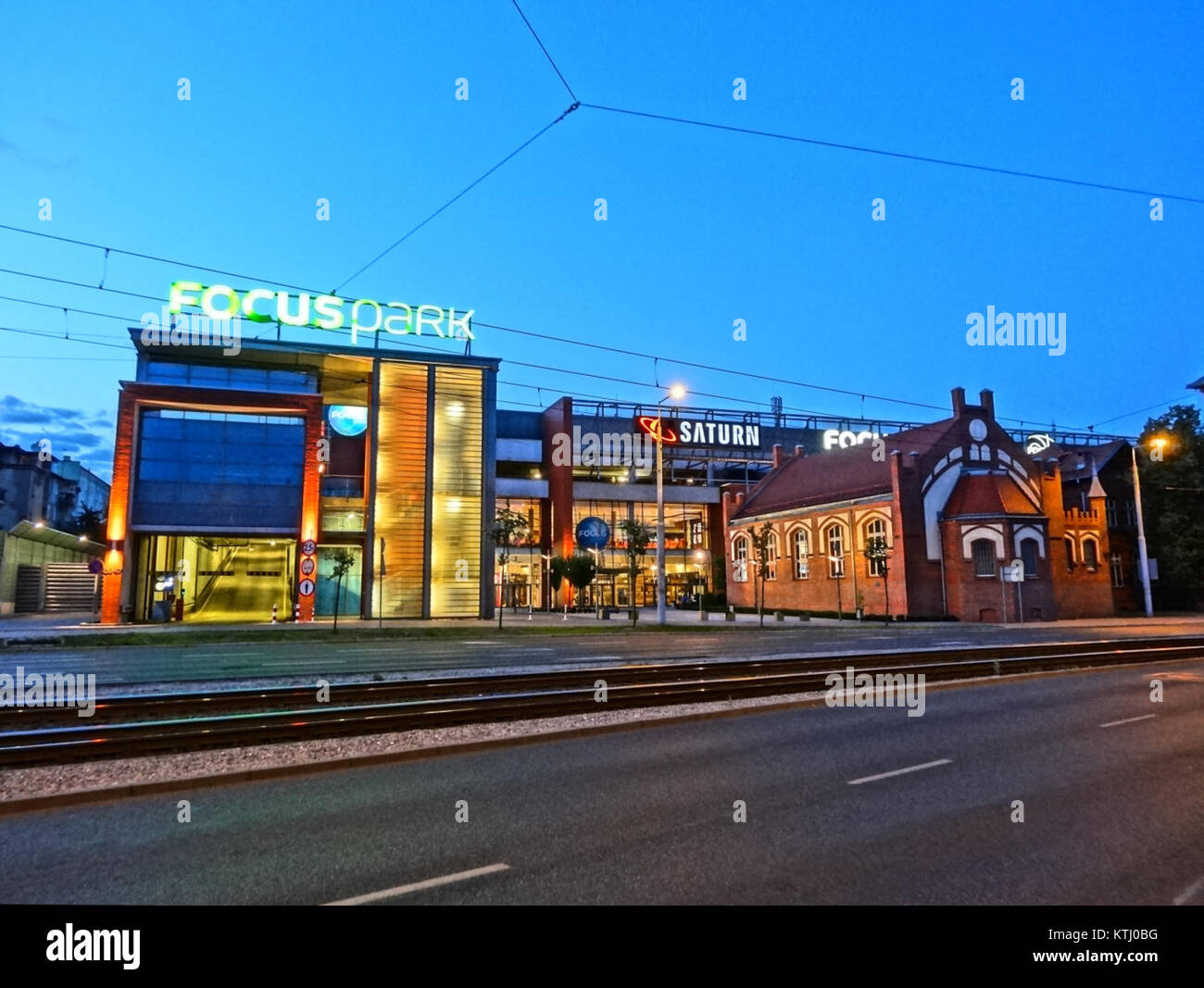 Immagine notturna di BDG FocusPark, un centro commerciale al coperto e centro di intrattenimento in Polonia. La foto mostra l'esterno illuminato dell'edificio, catturando l'atmosfera vibrante del centro commerciale di notte. Foto Stock