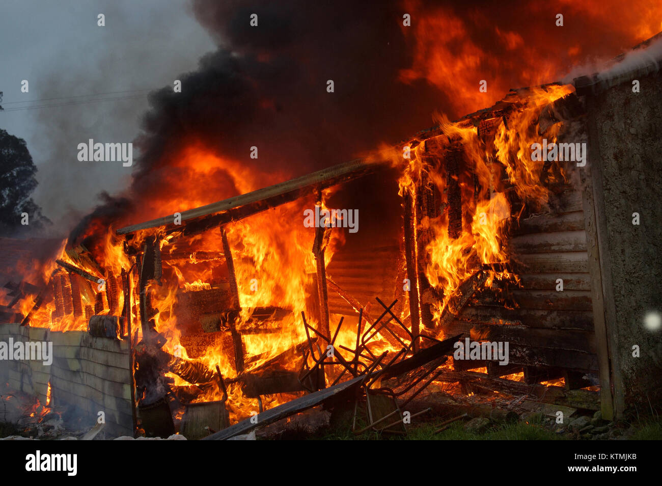 Le fiamme e il fumo salire dalla combustione di fattoria Foto Stock