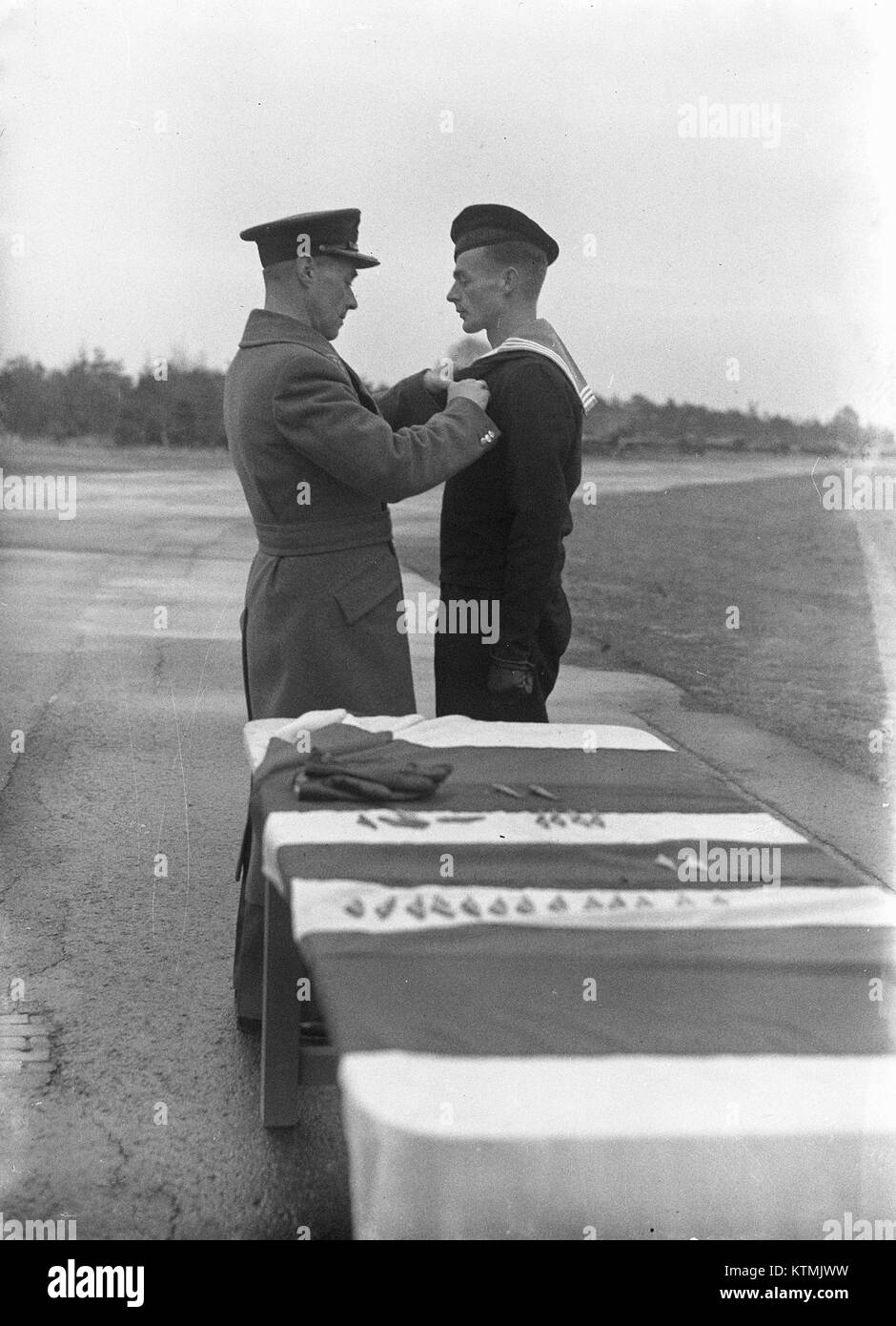 Questa immagine raffigura una cerimonia in cui gli ufficiali sono incaricati a Gilze Rijen, una base militare nei Paesi Bassi. Gilze Rijen è stato un sito importante per l'aviazione militare, servendo come base per la Royal Netherlands Air Force. La cerimonia mette in evidenza la tradizione e il significato dell'incarico di ufficiale militare nelle forze armate olandesi. Foto Stock