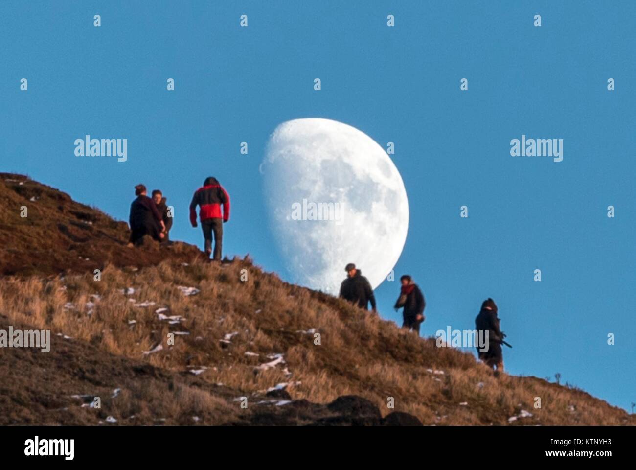 Edinburgh, Regno Unito. 28 dicembre, 2017. Walkers testa verso la luna che sorge durante gli ultimi minuti della giornata della luce sulle balze di Edimburgo Credito: ricca di Dyson/Alamy Live News Foto Stock
