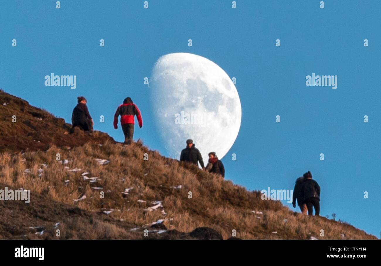 Edinburgh, Regno Unito. 28 dicembre, 2017. Walkers testa verso la luna che sorge durante gli ultimi minuti della giornata della luce sulle balze di Edimburgo Credito: ricca di Dyson/Alamy Live News Foto Stock