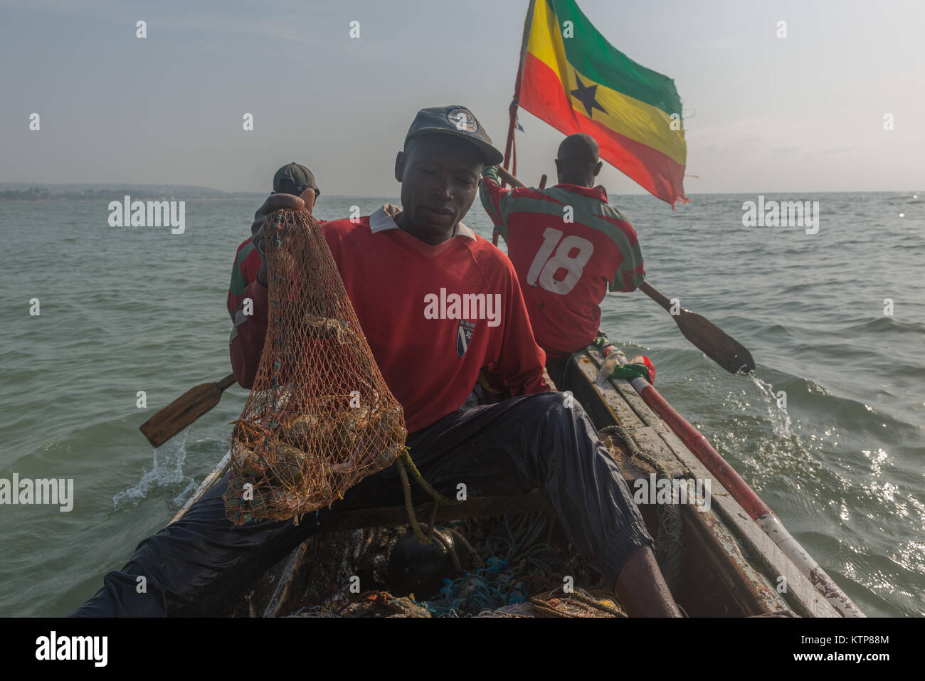 I pescatori nella loro barca open andare a pesca nelle prime ore del mattino. Essi racchetta da net a net per recuperare le loro catture, Kokrobite, maggiore Regione di Accra, Ghana Foto Stock
