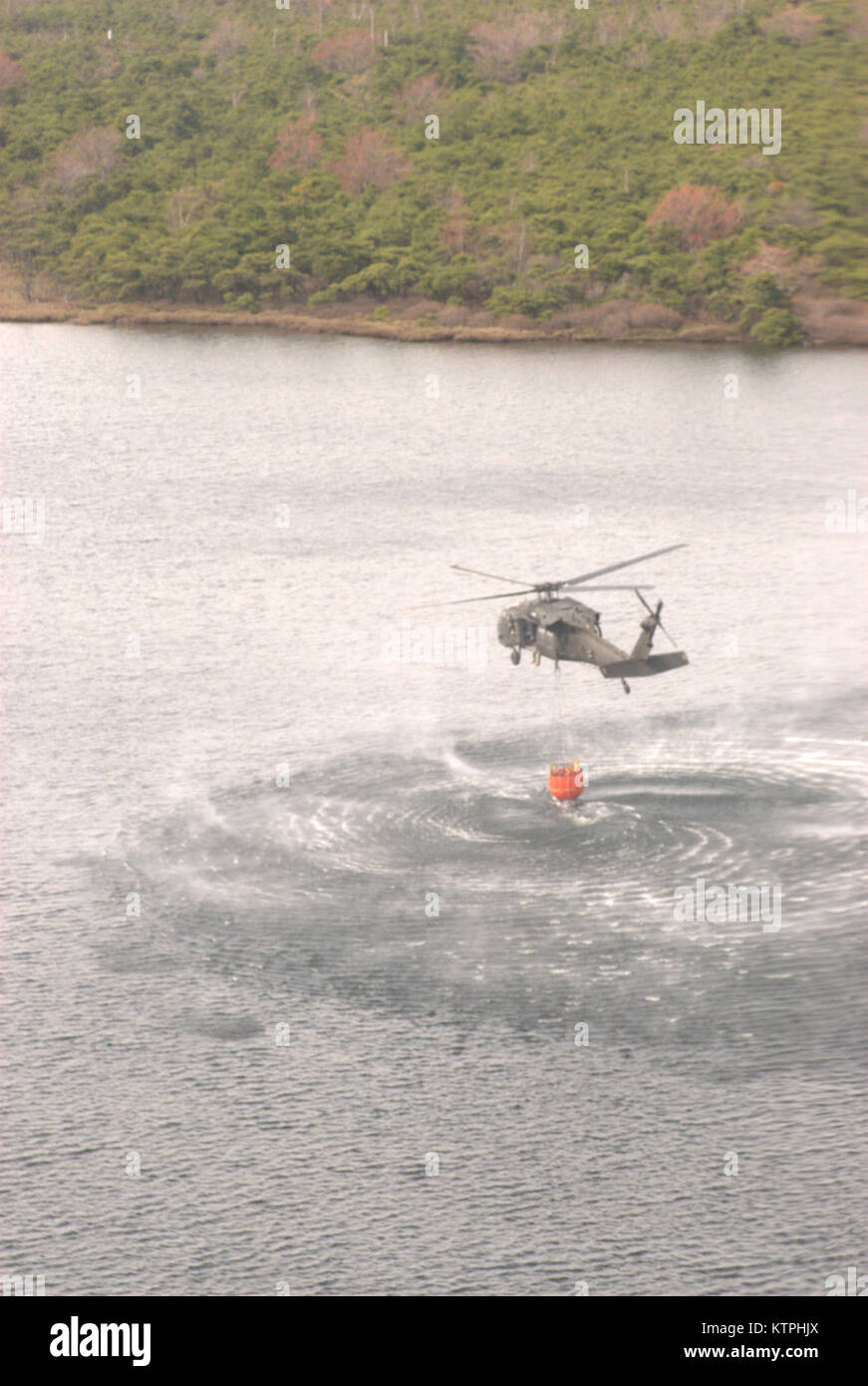 New York Esercito Nazionale Guardia personale di volo riempire il loro secchio di acqua da uno stato locale parco lago per aiutare nella lotta contro un incendio di foresta in cresta Shawangunk membro foresta vicino Summitville in Ulster County possono 5. Due UH-60 Blackhawk elicotteri e il suo equipaggio in base all'esercito Aviation Support Facility a Albany International Airport in Latham unite due ulteriori dello Stato di New York di elicotteri di polizia a goccia acqua lungo la linea di fuoco per aiutare a contenere il wildfire che è iniziata il 3 maggio. Gli equipaggi di acqua utilizzata benne, noto con il nome del marchio registrato di Bambi Bucket, a prelevare acqua dal vicino ai laghi o fiumi e Foto Stock