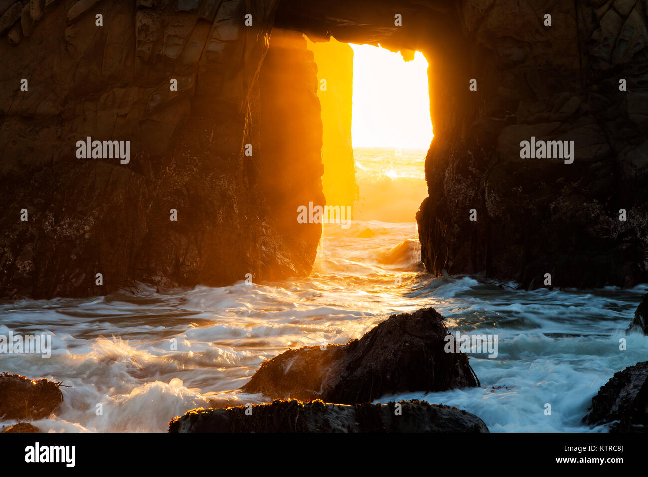 La luce del sole e navigare in streaming tramite toppa Arch a Pfeiffer Beach lungo la California's Big Sur Costa nei giorni precedenti e seguenti il winter s Foto Stock