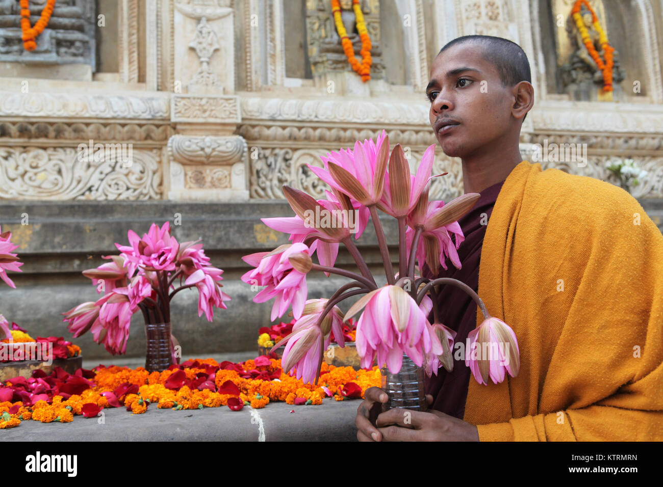 Ritratto di un monaco buddista con un'offerta di fiori di loto presso il tempio di Mahabodhi a Bodhgaya,, India Foto Stock