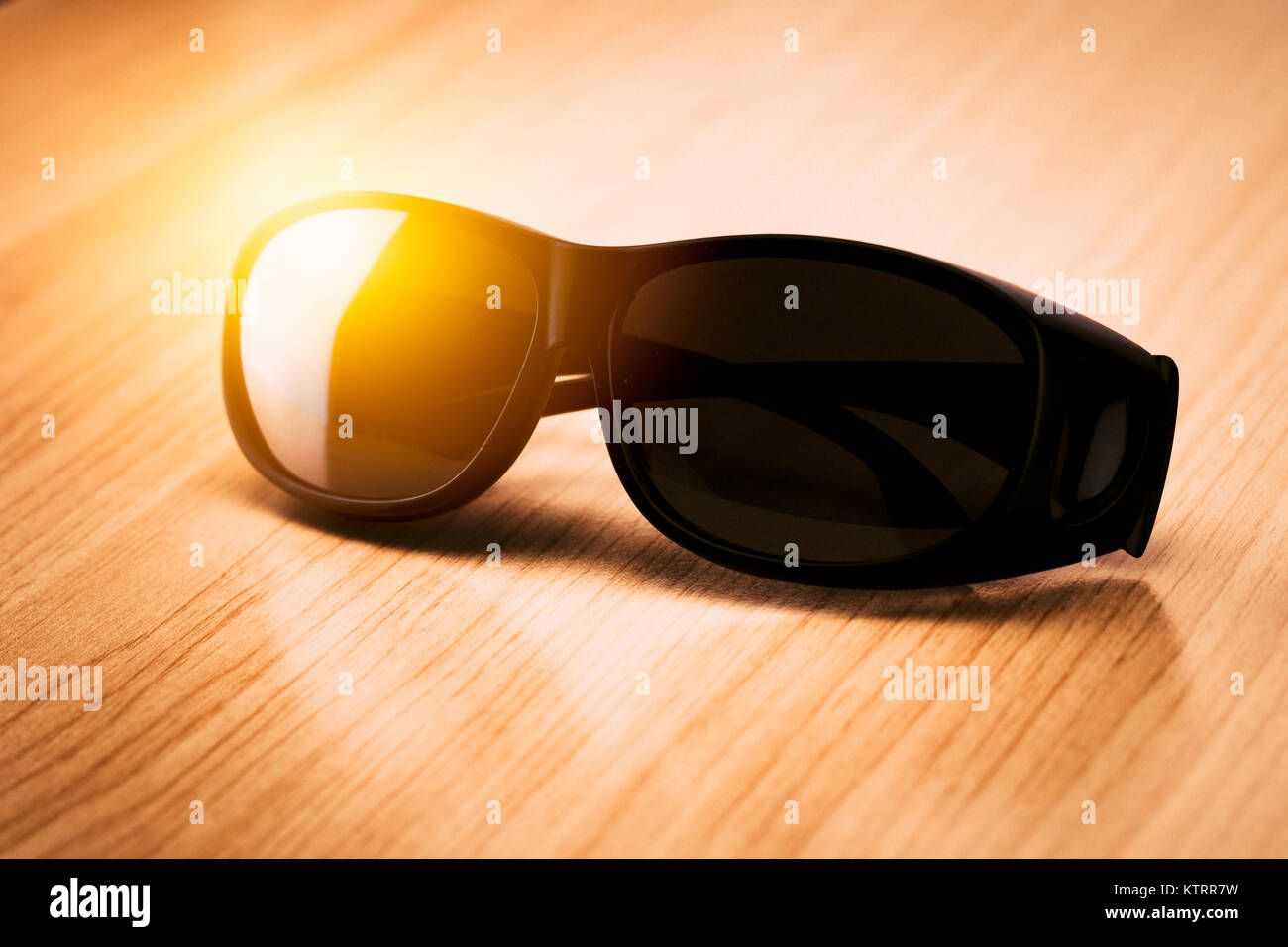 Occhiali da sole nero su tavola di legno con sole estivo luce protezione UV Foto Stock