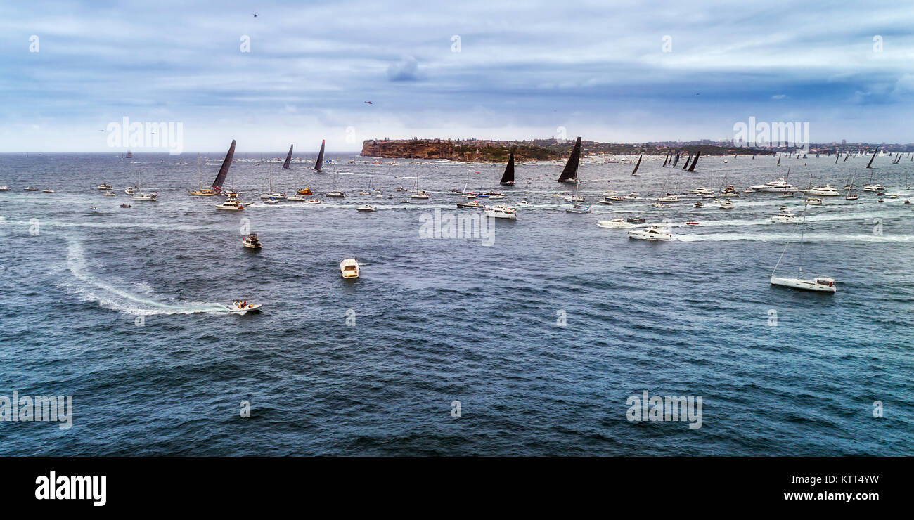 Leader di Sydney Hobart yacht race cancellazione da Sydney Harbour di girare a sud capo circondato da turisti e spettatori su navi e imbarcazioni. Foto Stock