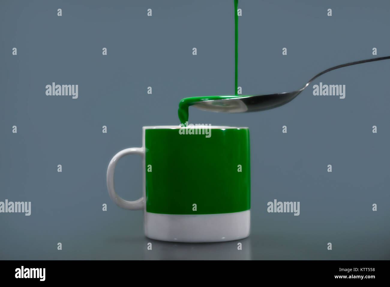 Versamento di liquido verde in una tazza verde Foto Stock