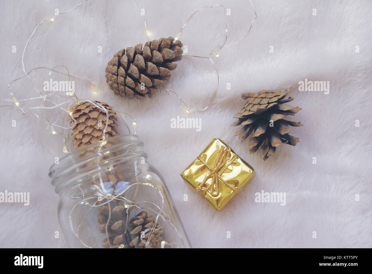 Primo piano di coni di pino natalizio, confezione regalo e luci fiabe in un vaso di vetro Foto Stock