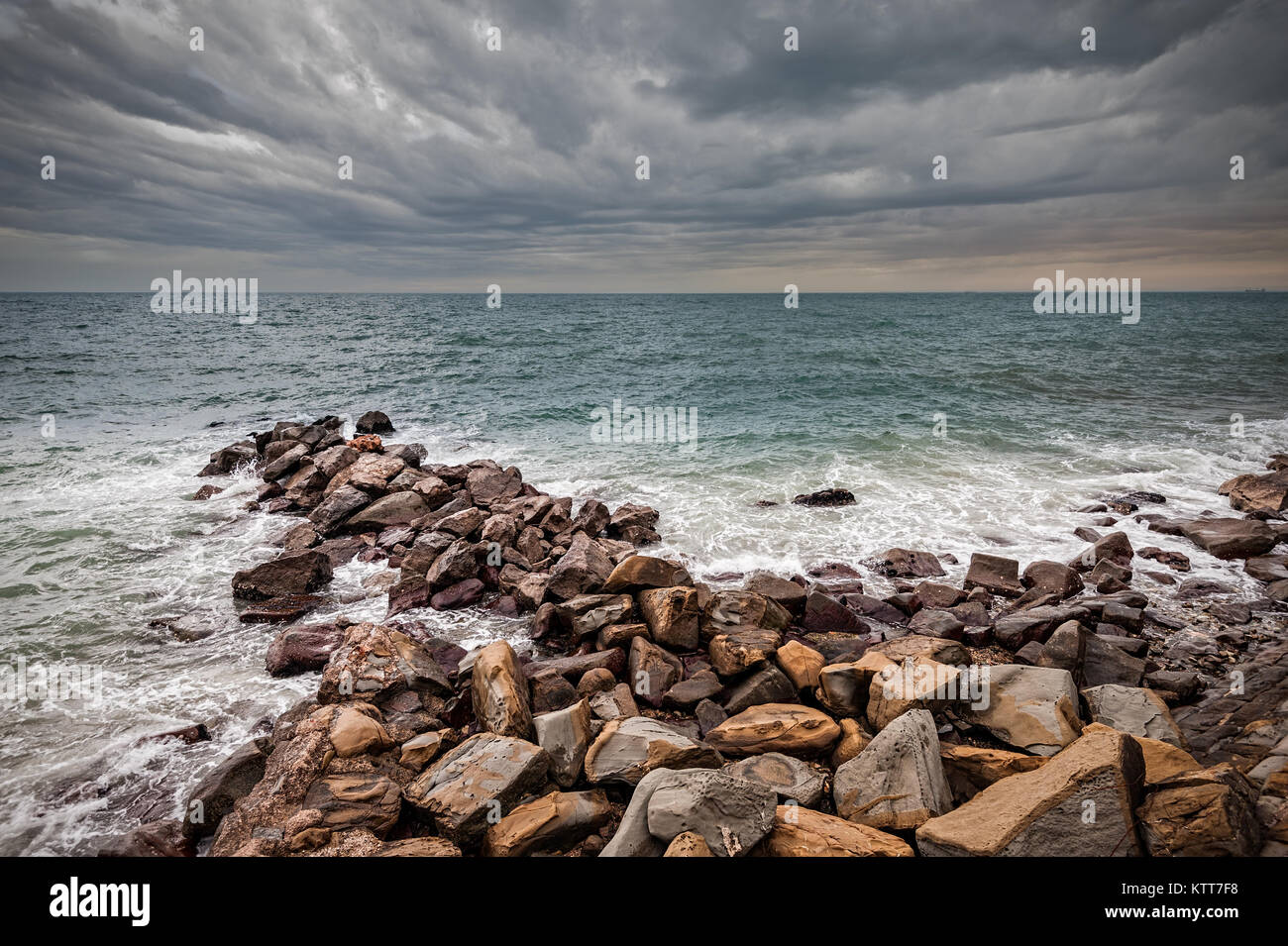Le onde del mare Adriatico si infrangono su una scogliera artificiale sotto il cielo in tempesta. Foto Stock