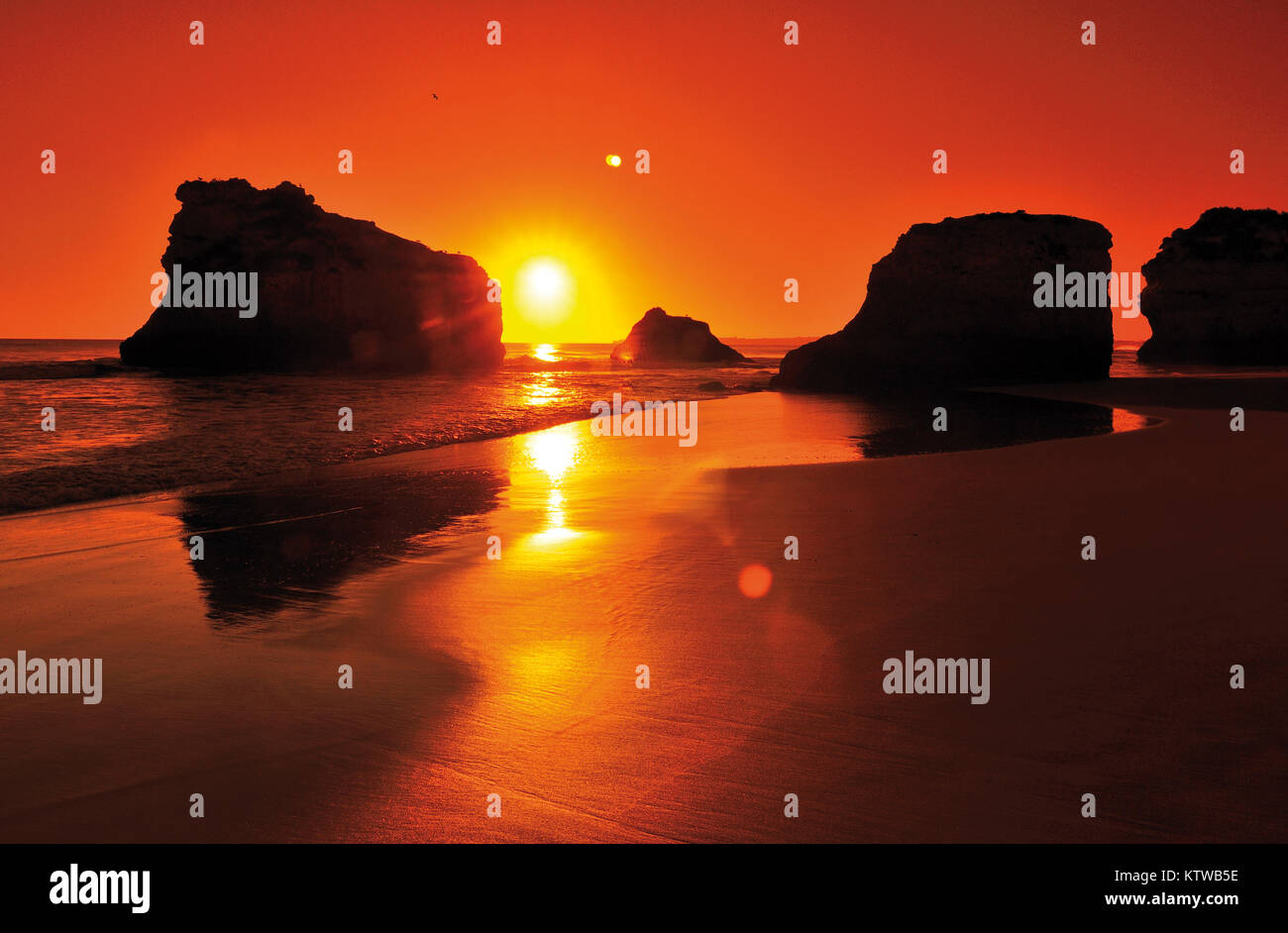 Scenic tramonto in spiaggia con orizzonte arancione e sagome di roccia Foto Stock