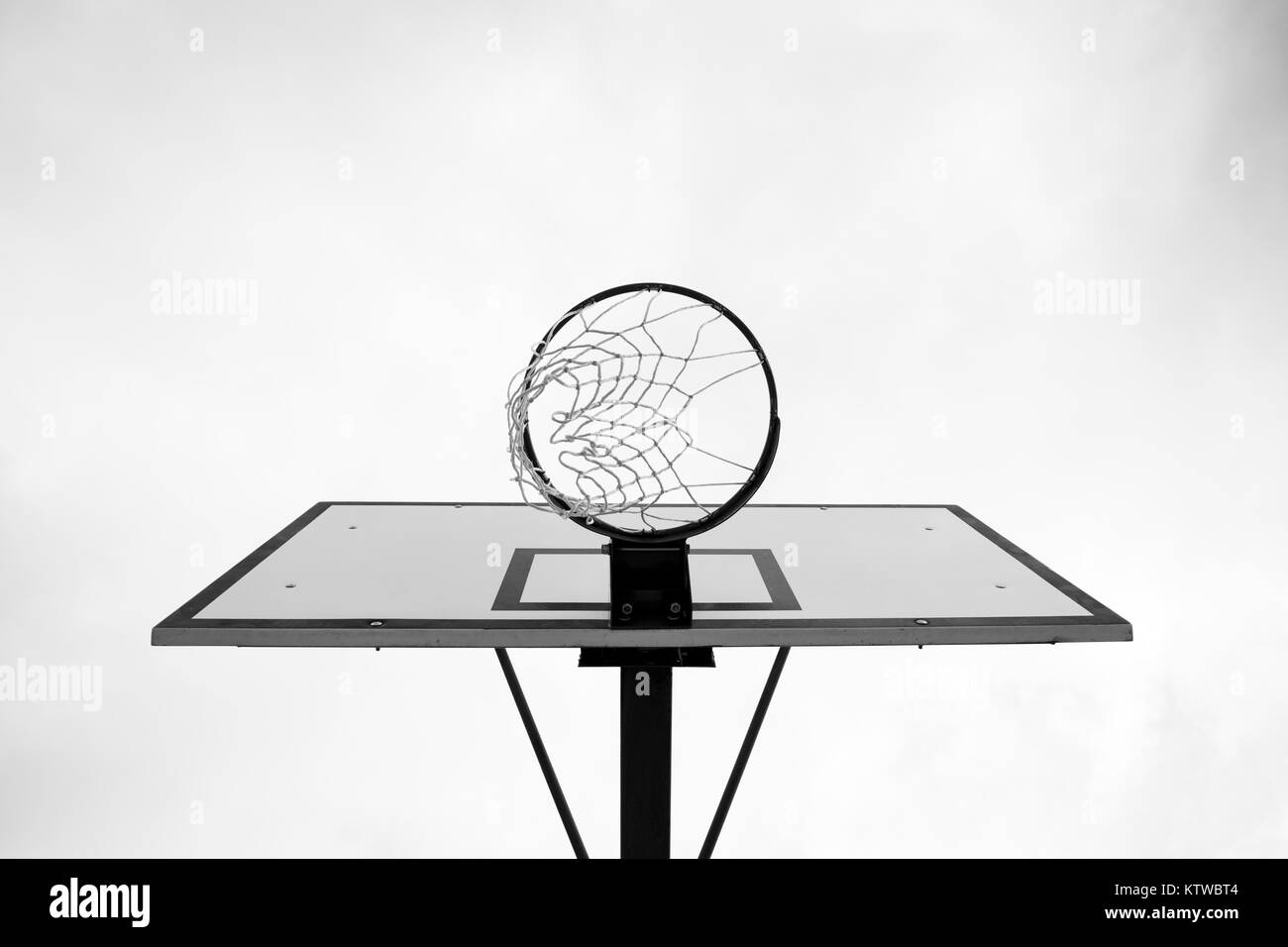 Immagine in bianco e nero di Basketball hoop, basket contro Bianco cielo nuvoloso. Al di fuori, street basketball. Foto Stock