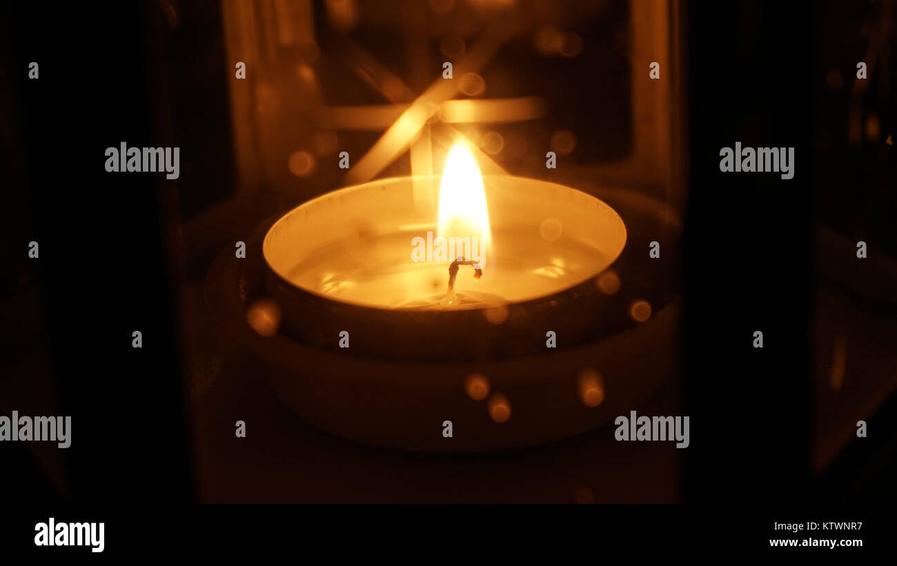 Candela di sfarfallio all'interno di una lanterna in vetro. Golden calda, con cera fusa e burt stoppino. Foto Stock