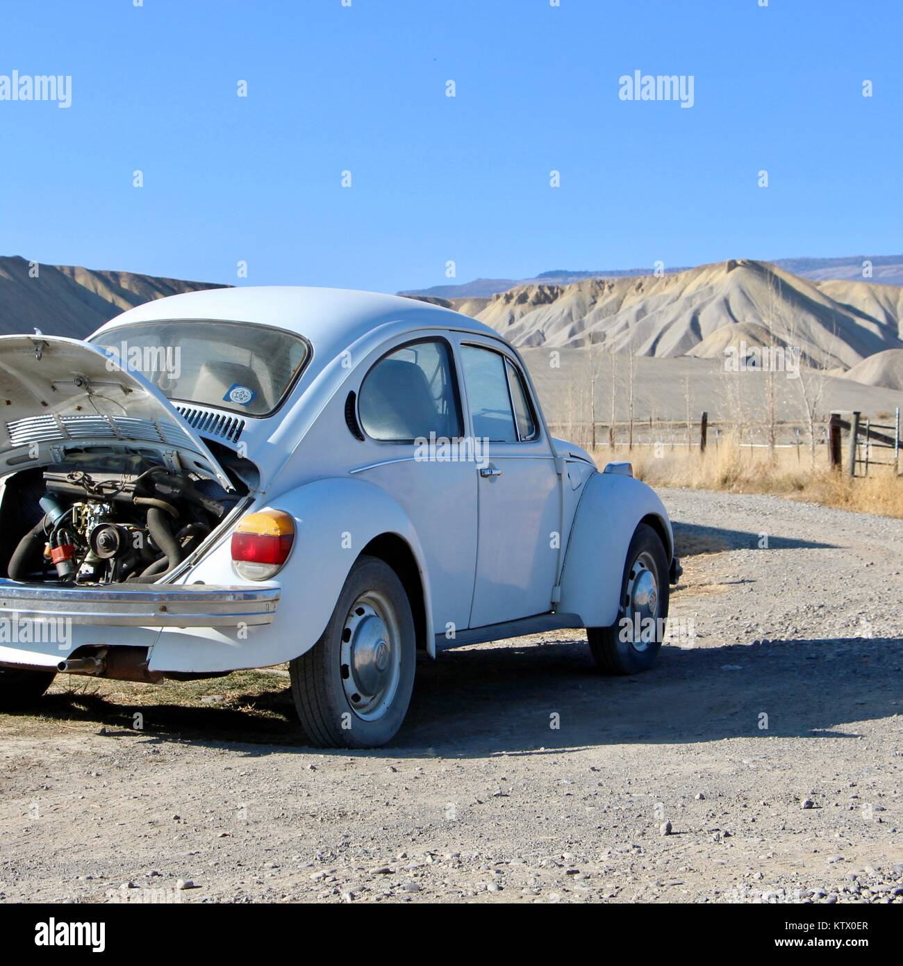 Un bianco Volkswagen maggiolino rivolta verso le dune del Delta, Colorado. Foto Stock