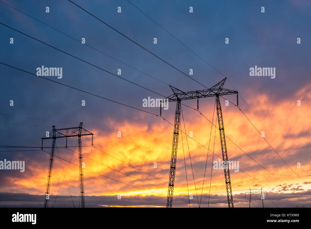 Alta tensione polo elettrico torri con la masterizzazione di sky tramonto in background e nuvole pesanti Foto Stock
