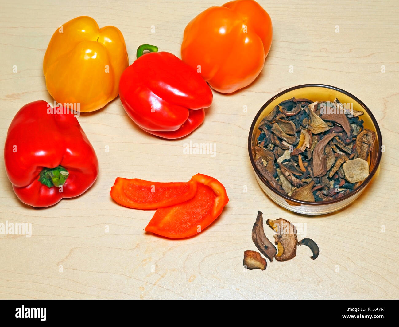 Preparazione alimentare, peperoni verdure e ciotola con funghi secchi su tavola di legno. Foto Stock