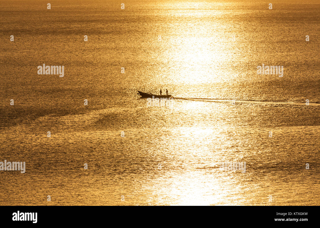 Pescatore tradizionale barca con due persone silhouette passando dalla luce del sole posto nel mezzo dell'oceano al tramonto, Bali, Indonesia Foto Stock